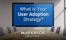 A conference room with a wooden table and a large tv screen. On the screen it reads, "What is Your User Adoption Strategy?" This urges readers to think through how data-driven adoption helps bolster digital adoption strategies.